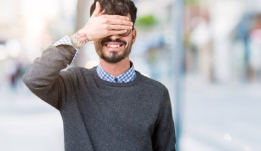 Yakışıklı genç gülümseyen ve gözler için sürpriz kapsayan yüz el ile gülüyor izole arka plan üzerinde gözlük takan adam akıllı. Kör kavramı.