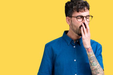 Yakışıklı delikanlı izole arka plan üzerinde gözlük el ağzıyla kapsayan yorgun esneme sıkılmış. Restless ve uyku hali.