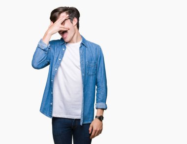 Mahcup ifadeyle parmaklarımın arasından seyir yüz ve gözler el ile kapsayan şok bakmak izole arka plan üzerinde gözlük takan genç yakışıklı adam.