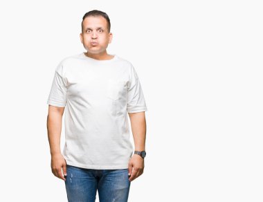 Orta yaş Arap adam eğlenceli yüz ile izole arka plan kabarık yanakları üzerinde beyaz tişört wearig. Ağız hava ile şişirilmiş, çılgın ifade.