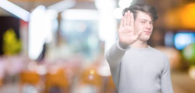 Yakışıklı delikanlı üzerinde kış kazak giyen elin avuç durağı şarkı yapıyor arka plan izole. Negatif ve ciddi bir jest yüz ifadesiyle uyarı.