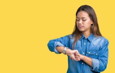 Genç güzel esmer kadın kol saati, rahat ve kendinden emin zamanında kontrol izole arka plan üzerinde mavi kot gömlek giymiş