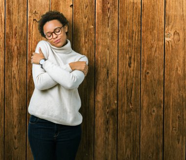 Genç güzel Afrikalı-Amerikalı kadın gözlük izole üzerinde emin gülümseyen Hugging kendini mutlu ve olumlu, arka plan. Kendi aşk ve öz bakım