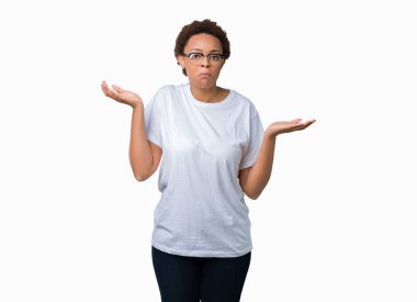 Güzel genç Afro-Amerikan kadın üzerinde gözlük takan arka plan clueless ve şaşkın bir ifadeyle kollar ve eller kaldırdı izole. Şüphe kavramı.