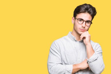 Çene düşünme hakkında soru, dalgın ifade üzerine el ile izole arka plan üzerinde gözlük takan yakışıklı delikanlı. Düşünceli yüzüyle gülümsüyor. Şüphe kavramı.
