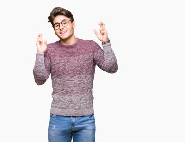 Umut ve gözleri kapalı geçiş parmaklarıyla gülümseyen izole arka plan üzerinde gözlük takan yakışıklı delikanlı. Şans ve batıl kavramı.