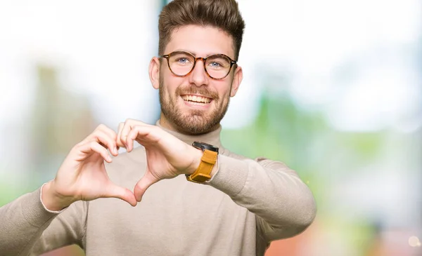 若いハンサムなビジネス男が眼鏡をかけてハートマークと手で形を示す愛の笑顔します ロマンチックな概念 — ストック写真