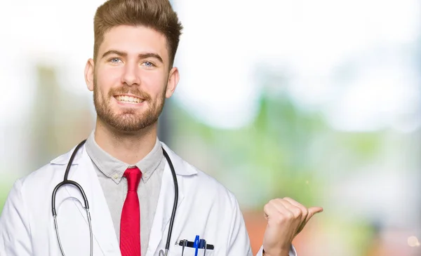 探していると親指側に上向きの幸せそうな顔を浮かべて医療のコートを着ている若いハンサムな医者の男 — ストック写真