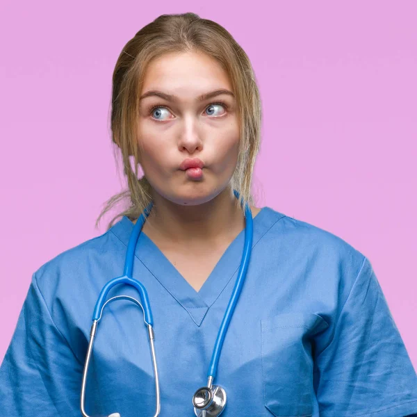 若い白人医師女性の外科医の制服を着ては 狂気とコミカルなジェスチャーで背景作る魚の顔を分離しました 面白い表現 — ストック写真
