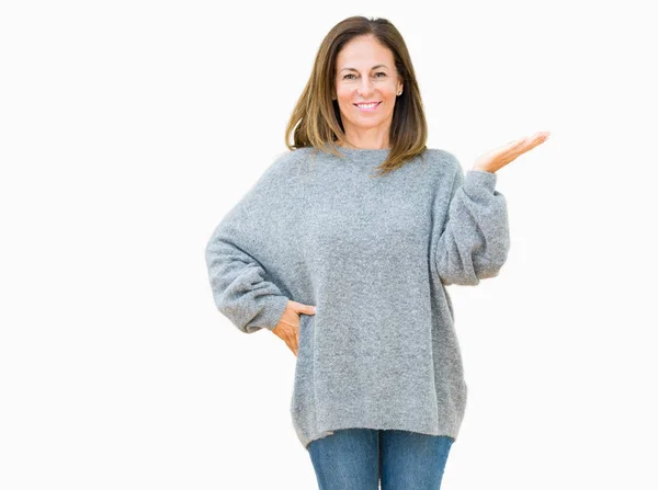 陽気な提示とカメラを見て手の手のひらで指している笑みを浮かべて分離の背景に冬のセーターを着て美しい中年女性 — ストック写真