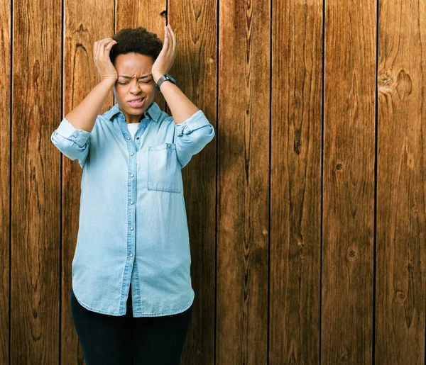 Genç güzel Afrikalı-Amerikalı kadın izole arka plan çünkü umutsuz ve stresli baş ağrısı acı yüzünden acı ve migren. Ellerini kafasına.