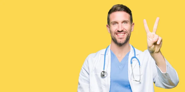 上医療制服を着てハンサムな医者男分離を示す背景と自信を持って 幸せな笑みを浮かべている間 つ番号を指で上向き — ストック写真
