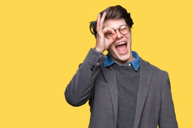 Gülümseyen, parmakları ile mutlu yüz üzerinden seyir göz el ile ok jest yapıyor izole arka plan üzerinde gözlük takan genç yakışıklı iş adamı.