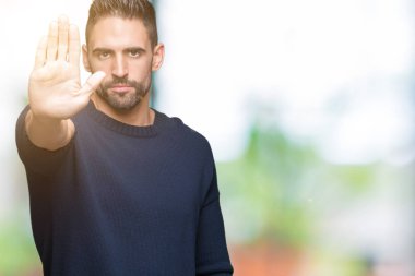 Elin avuç durağı şarkı yapıyor izole arka plan üzerinde kazak giyen genç yakışıklı adam. Negatif ve ciddi bir jest yüz ifadesiyle uyarı.