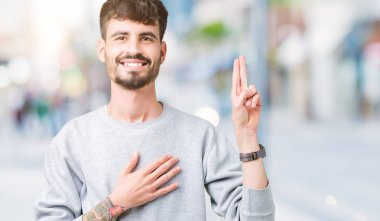 Genç yakışıklı adam giyen kazak izole üzerinde arka plan Swearing göğüs ve bir sadakat sözü yemin yapma parmaklar, el ile