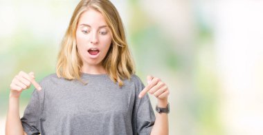 Güzel genç kadın giyiyor büyük boy rahat t-shirt üzerine izole arka plan aşağı işaret parmakları ile reklam, sürpriz yüz ve açık ağız gösterilen