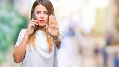 Genç güzel kadın konuşma arama açık eliyle dur işareti ile ciddi ve kendine güvenen ifade, savunma jest yapıyor izole arka plan üzerinde Smartphone kullanarak