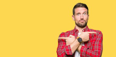 Yakışıklı adam giyiyor rahat forması ile her iki taraf için işaret parmakları, farklı yönde katılmıyorum