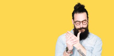 Uzun saçlı ve sakal giyen gözlük ile genç hipster adam ellerde ve parmaklarda ağrı acı, artrit iltihabı