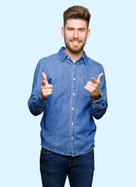 Casual denim gömlek işaret parmakları için fotoğraf makinesi ile mutlu ve komik yüz giyen genç yakışıklı sarışın adam. İyi enerji ve vibes.