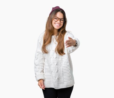 Tebrik ve konuksever dost sunan karşılıklı gülümseyen izole arka plan üzerinde gözlük ve kış şapka giyen genç güzel esmer hipster kadın. Başarılı iş.