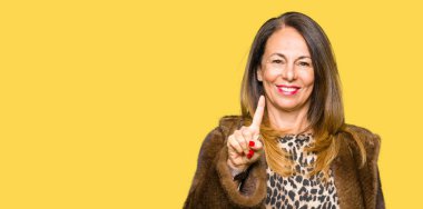 Gösterilen ve parmak numara ile yukarı dönük kendinden emin ve mutlu gülümseyen güzel orta yaş zarif kadın giyiyor vizon ceket.