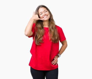 Genç güzel esmer kadın telefon üzerinde konuşmak gibi el ve parmaklar ile telefon jest yapıyor gülümseyen izole arka plan üzerinde kırmızı t-shirt giyiyor. İletişim kavramları.