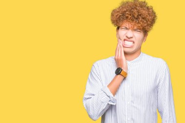 Diş ağrısı veya dişlerde dişlerle ilgili hastalık nedeniyle ağız acı ifadesi ile el ile dokunmak şık gömlek giymiş afro saçlı genç yakışıklı iş adamı. Diş hekimi kavramı.