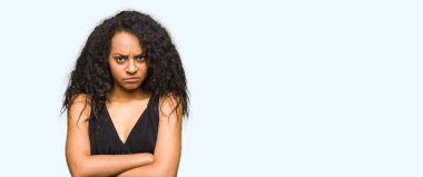 Kıvırcık saçlı moda etek şüpheci ve gergin giyen genç güzel kız, çapraz kolları ile yüz üzerinde onaylanma ifadesi. Negatif kişi.