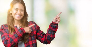 Gülümseyen ve iki elleri ve parmakları ile tarafına işaret kamera bakarak izole arka plan üzerinde bir ceket giyen genç güzel esmer kadın.