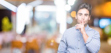 Genç yakışıklı iş adamı dudaklarında parmak ile sessiz olmanı izole arka plan üzerinde. Sessizlik ve gizli kavramı.