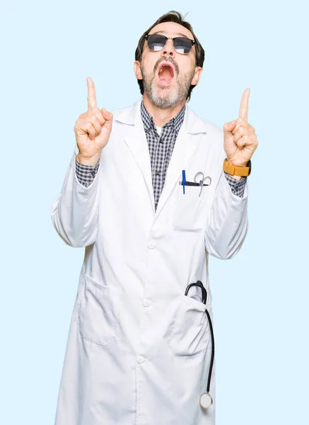 英俊的中年医生戴着太阳镜的男子惊讶和惊讶地抬起头来 用手指指指点点 举起双臂 — 图库照片
