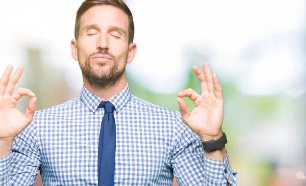 Handsome business man wearing tie relax and smiling with eyes closed doing meditation gesture with fingers. Yoga concept.