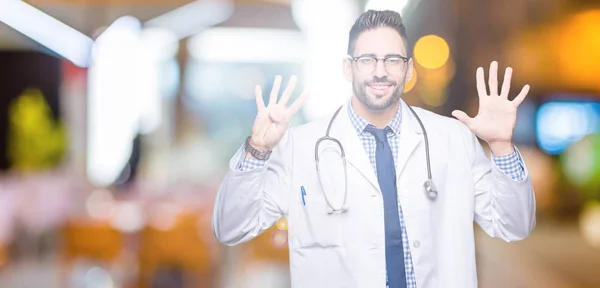 英俊的年轻医生在孤立的背景显示和指向用手指九号 同时微笑着自信和快乐 — 图库照片