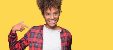 Güzel genç Afro-Amerikan kadın yüzünde gülümseme ile kendinden emin görünüyorsun, kendini gururlu ve mutlu parmakları ile işaret izole arka plan üzerinde gözlük.