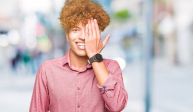 Afro saçlı Genç yakışıklı iş adamı yüz ve sürpriz duygu kendine güvenen gülümseme ile el ile bir göz kaplayan.