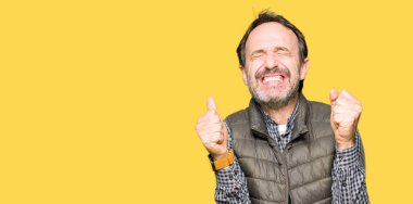 Orta yaş yakışıklı adam kızgın ve silah ile başarı için deli kutluyor kış yelek giyen kaldırdı ve heyecanlı çığlık gözler kapalı. Kazanan kavramı