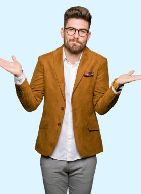 Gözlük clueless ve şaşkın bir ifadeyle kollar ve eller kaldırdı giyen genç yakışıklı iş adam. Şüphe kavramı.