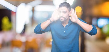 Yakışıklı delikanlı kulak jest, dedikodu için meraklı her iki ellerde dinliyoruz izole arka plan üzerinde. İşitme sorunu, sağır