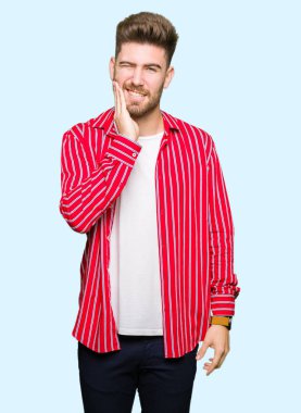 Diş ağrısı veya dişlerde dişlerle ilgili hastalık nedeniyle ağız acı ifadesi ile el ile dokunmak kırmızı gömlek giymiş yakışıklı delikanlı. Diş hekimi kavramı.