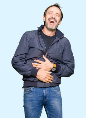 Bir ceket giyen orta yaş yakışıklı adam gülen ve komik deli şaka çünkü yüksek sesle zor gülüyor. Mutlu ifade.