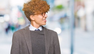 Genç yakışıklı iş adamı ile uzak tarafına yüzünde, doğal ifade gülümseme ile seyir gözlüklü afro. Kendine güvenen gülüyor.