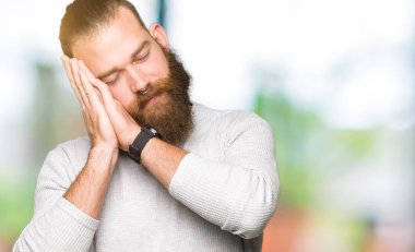 Kapalı gözleri ile gülümseyen iken rahat kazak uyku yorgun rüya ve eller ile poz giyen genç sarışın adam.