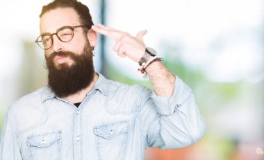 Uzun saç ve sakal giyen genç hipster adamla çekim ve öldürmek kendini el ve parmaklara baş, intihar jest işaret gözlük.