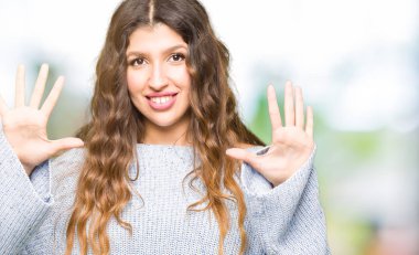 Gösterilen ve parmakları ile işaret genç güzel kadın giyiyor kış kazak kendinden emin ve mutlu gülümseyerek süre on numara.