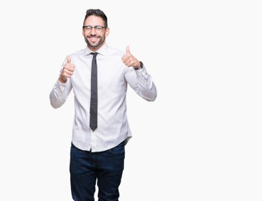 Genç yakışıklı iş adamı izole arka plan başarı işareti el ile pozitif jest yapıyor üzerinde gözlük takan başparmak gülümseyen ve mutlu. Neşeli bir ifadeyle, kazanan jest kameraya bakıyor.