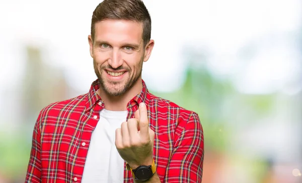 Handsome man wearing casual shirt Beckoning come here gesture with hand inviting happy and smiling