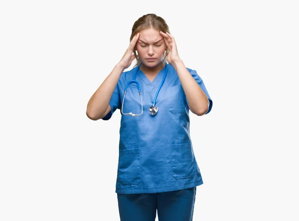 年轻的高加索医生妇女穿外科医生制服在孤立的背景与手在头上为痛苦在头由于重音 患有偏头痛 — 图库照片