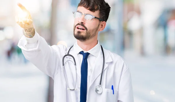 Młody Lekarz Człowiek Sobie Szpital Płaszcz Białym Tle Wskazując Palcem — Zdjęcie stockowe