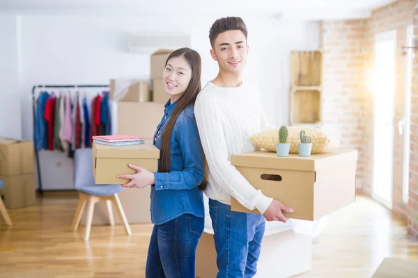 Schönes junges asiatisches Paar sieht glücklich aus, als es Pappschachtel hält — Stockfoto